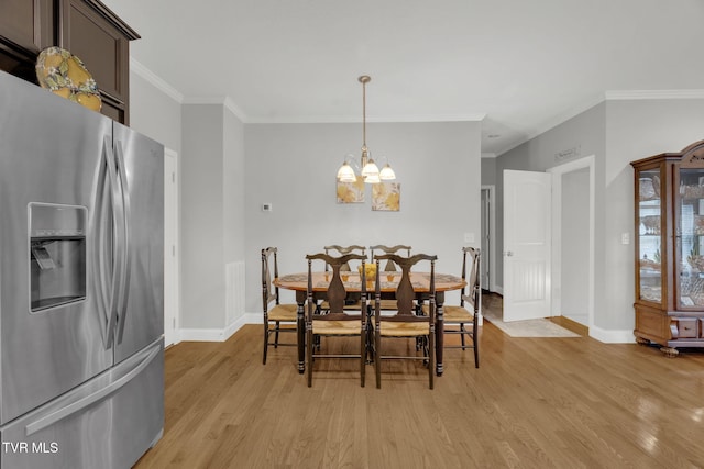 dining space featuring light wood-type flooring, a notable chandelier, and crown molding