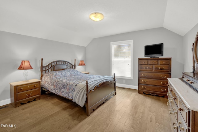 bedroom with lofted ceiling, light wood-style flooring, and baseboards