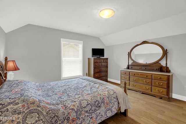 bedroom featuring baseboards, vaulted ceiling, and wood finished floors