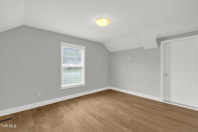 bonus room featuring baseboards, visible vents, vaulted ceiling, and wood finished floors