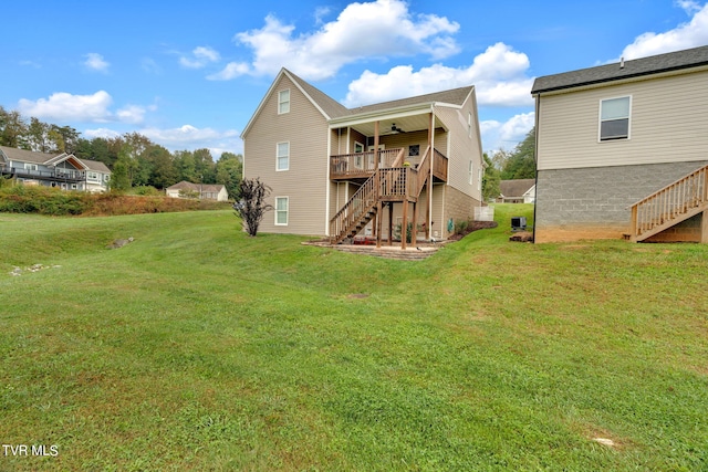 rear view of house with a ceiling fan, a yard, a wooden deck, and stairs