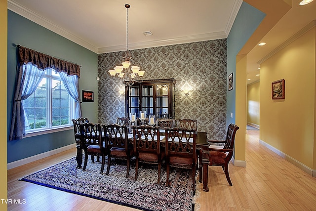 dining area with light hardwood / wood-style flooring, a chandelier, and crown molding