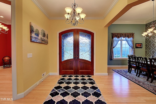 entrance foyer with crown molding, light hardwood / wood-style flooring, french doors, and a chandelier