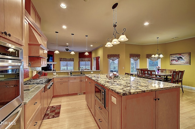 kitchen featuring pendant lighting, light wood-type flooring, stainless steel appliances, and a kitchen island