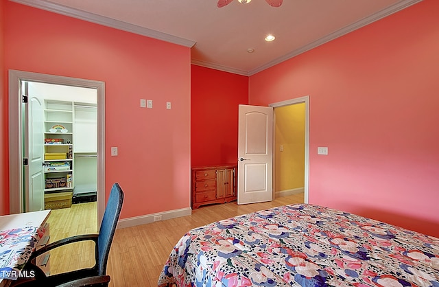 bedroom featuring light wood-type flooring, crown molding, a spacious closet, and a closet