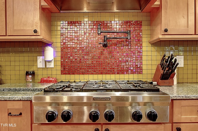 kitchen with light brown cabinetry, light stone countertops, and tasteful backsplash