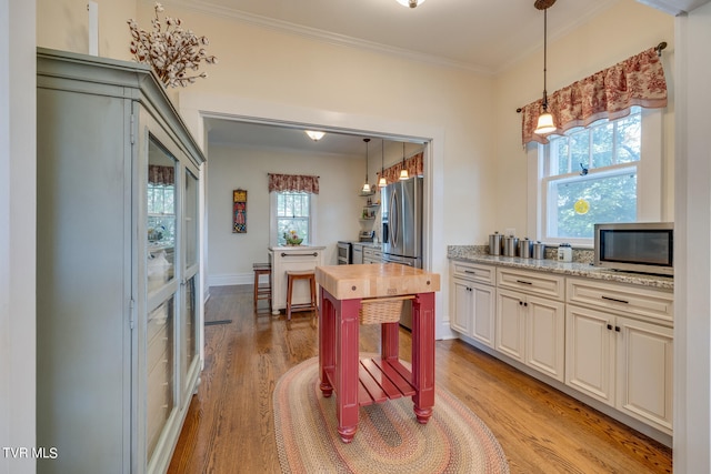 kitchen featuring appliances with stainless steel finishes, light wood-type flooring, a healthy amount of sunlight, and wood counters