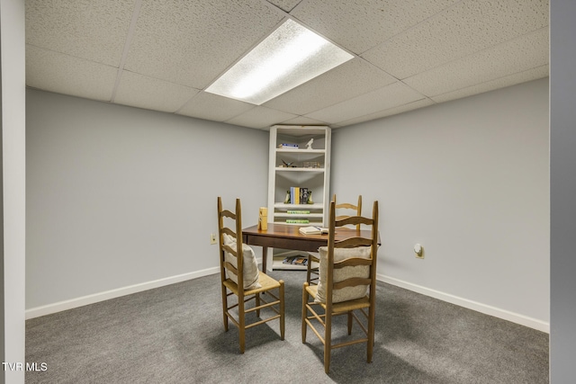 dining room with a paneled ceiling and dark colored carpet