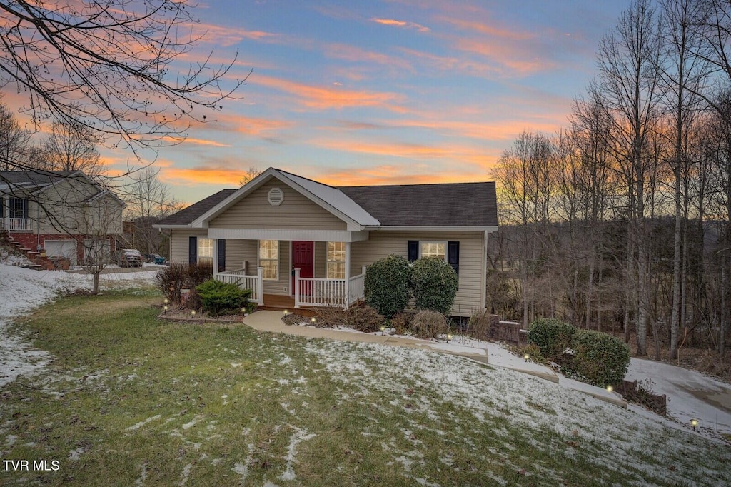 ranch-style home featuring a lawn and covered porch