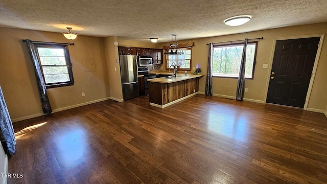 kitchen with stainless steel appliances, hanging light fixtures, kitchen peninsula, and a wealth of natural light