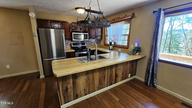 kitchen featuring appliances with stainless steel finishes, kitchen peninsula, dark hardwood / wood-style flooring, and a wealth of natural light