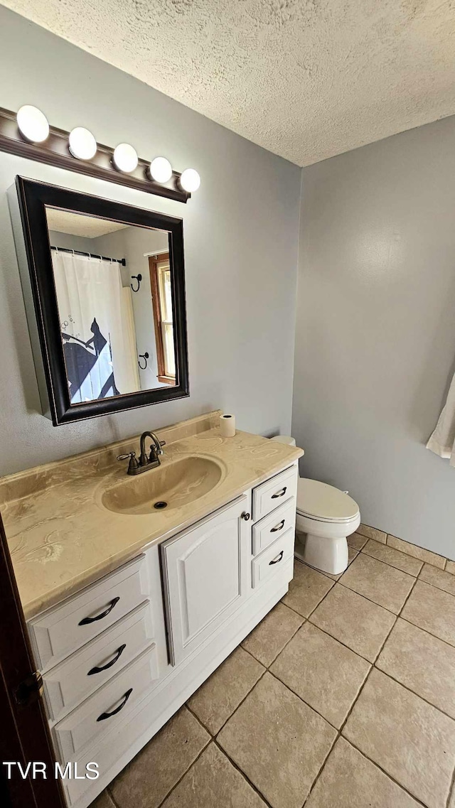 bathroom featuring tile patterned floors, a textured ceiling, vanity, and toilet