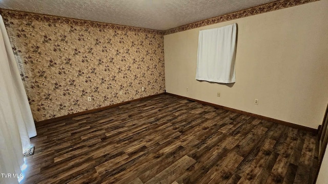 empty room with a textured ceiling and dark wood-type flooring