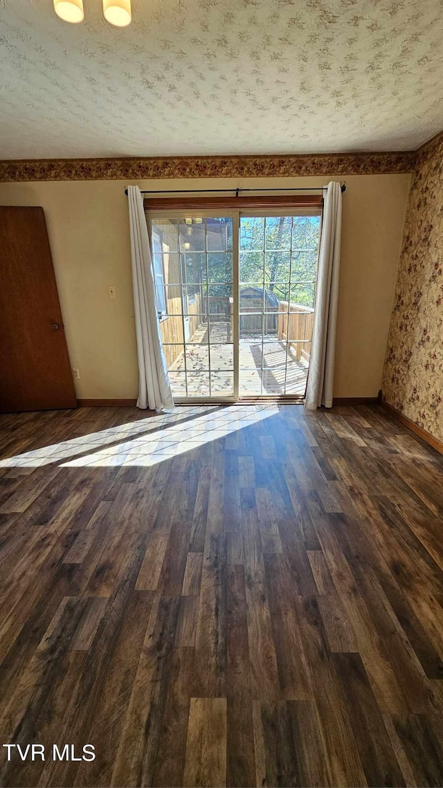 spare room with a textured ceiling and dark hardwood / wood-style flooring