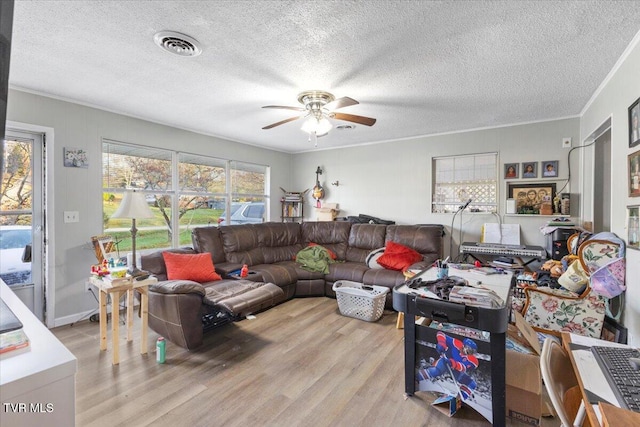 living room with crown molding, ceiling fan, light hardwood / wood-style floors, and a textured ceiling