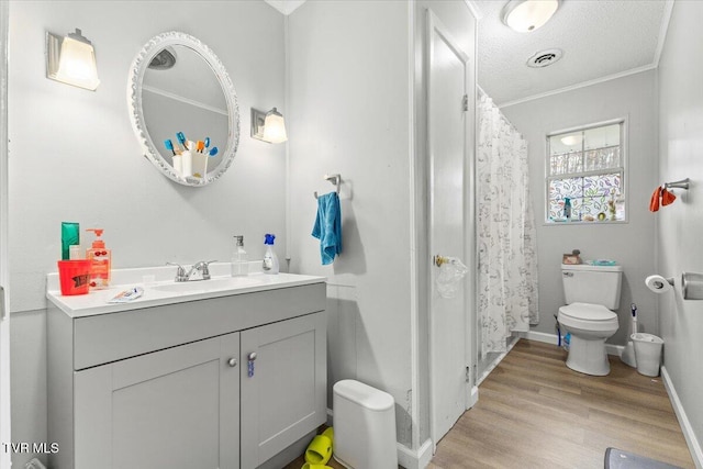 bathroom featuring vanity, a textured ceiling, crown molding, wood-type flooring, and toilet