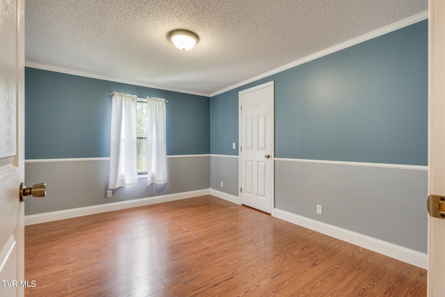 empty room with a textured ceiling, crown molding, and hardwood / wood-style floors