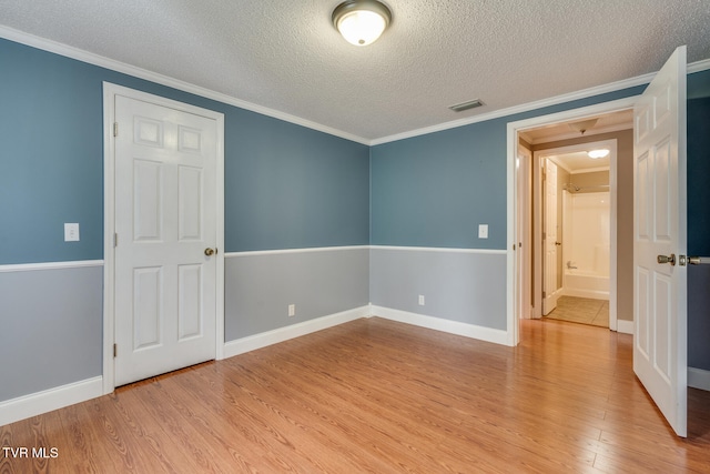 unfurnished room featuring ornamental molding, light hardwood / wood-style flooring, and a textured ceiling