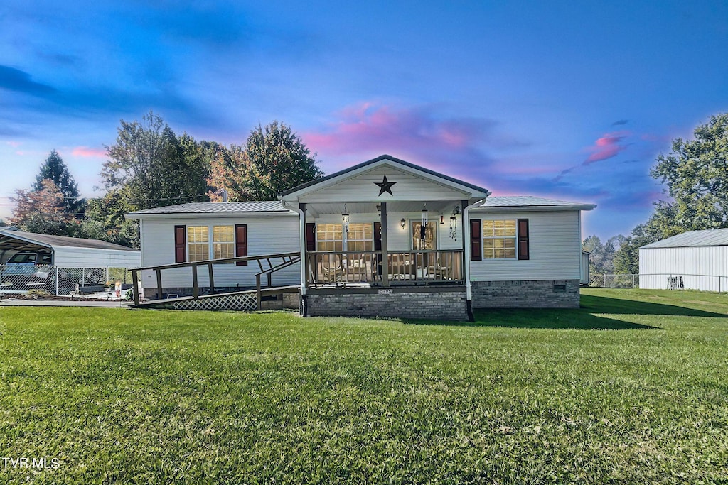 view of front of house featuring a carport, a porch, and a yard