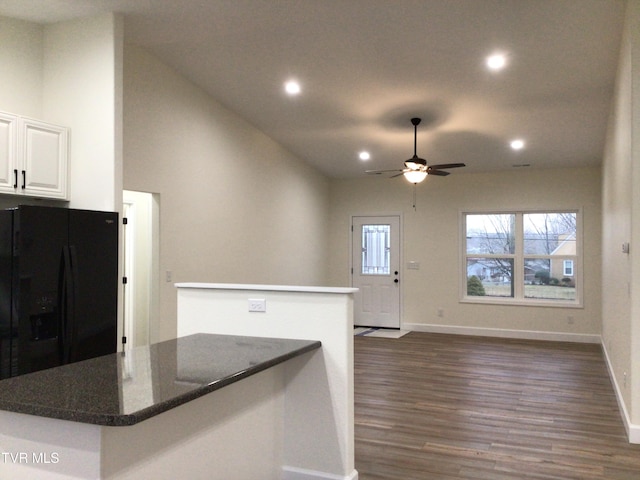 kitchen with black refrigerator with ice dispenser, dark stone counters, ceiling fan, dark hardwood / wood-style flooring, and white cabinetry