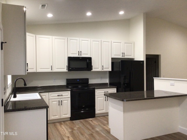 kitchen featuring black appliances, lofted ceiling, white cabinetry, and sink