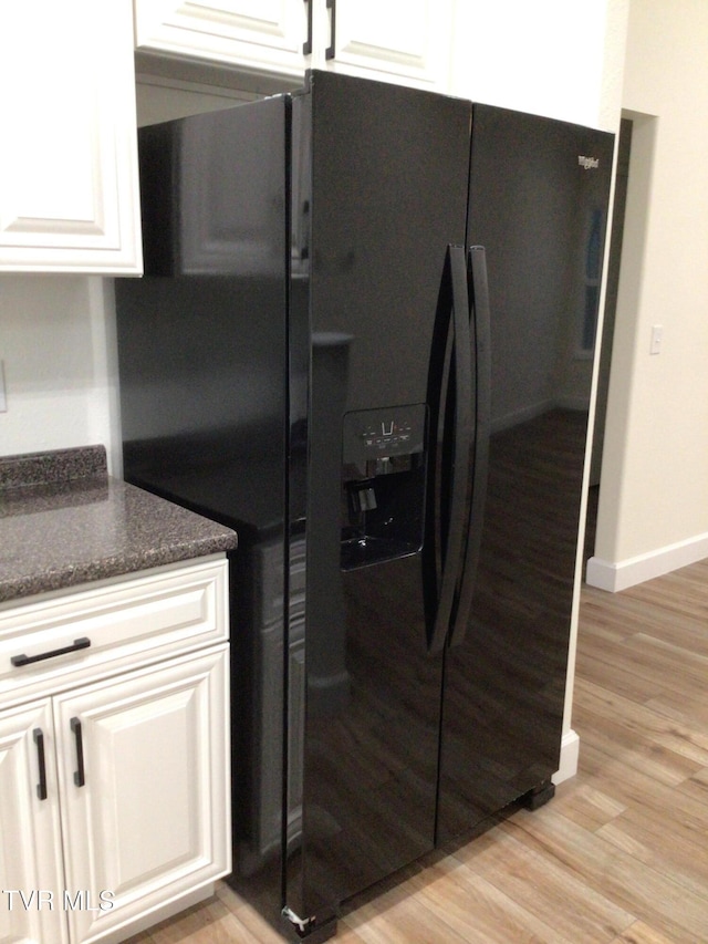 kitchen with white cabinets, light wood-type flooring, and black refrigerator with ice dispenser