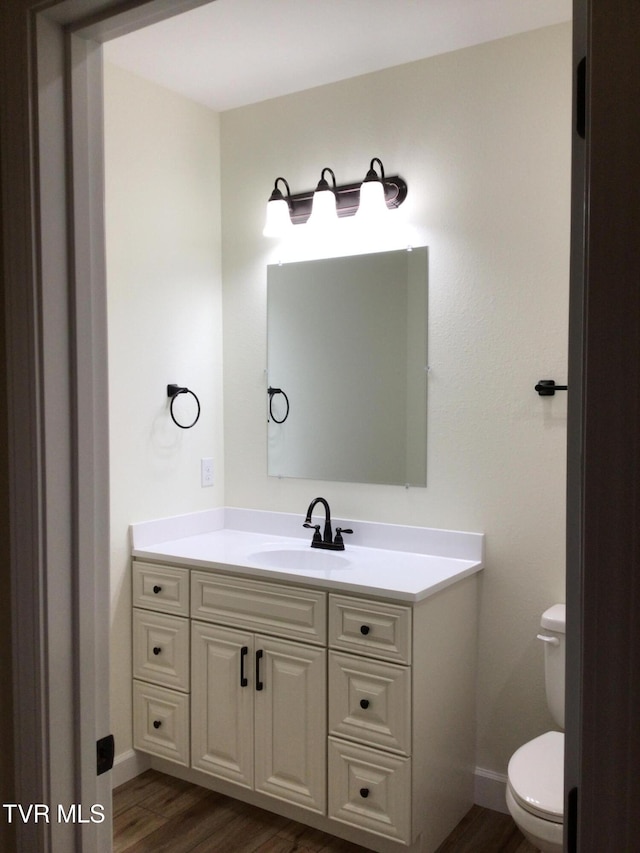 bathroom featuring toilet, vanity, and hardwood / wood-style flooring