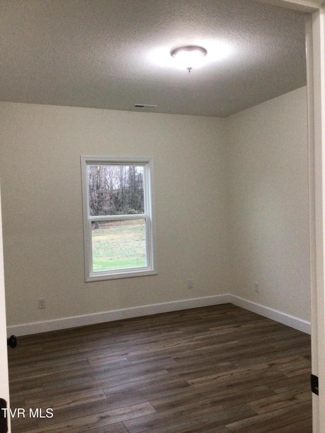 spare room with dark hardwood / wood-style floors and a textured ceiling