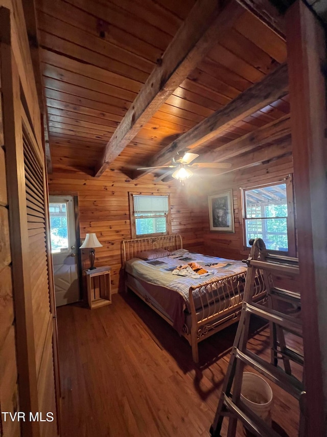 bedroom featuring multiple windows, wooden walls, and hardwood / wood-style floors