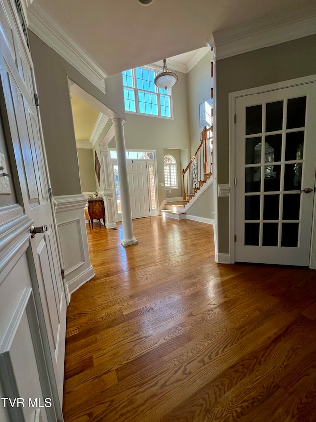 foyer entrance featuring ornamental molding, ornate columns, and wood-type flooring