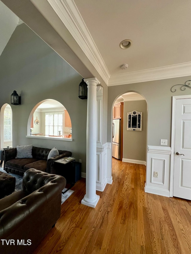 corridor featuring crown molding, hardwood / wood-style flooring, and decorative columns