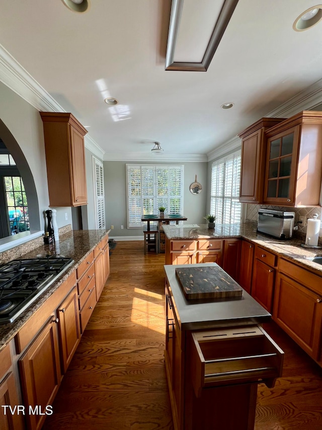 kitchen featuring backsplash, gas stovetop, ornamental molding, dark hardwood / wood-style floors, and a center island