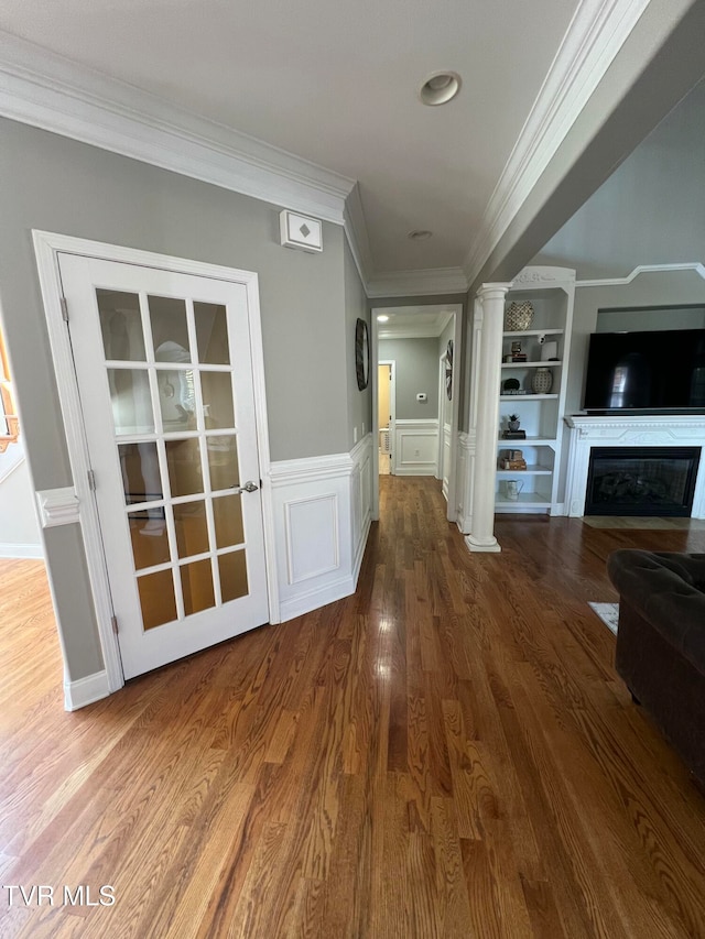 corridor with ornate columns, crown molding, and hardwood / wood-style floors