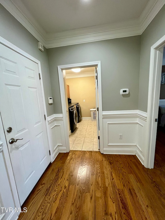 interior space with crown molding, independent washer and dryer, and light hardwood / wood-style floors