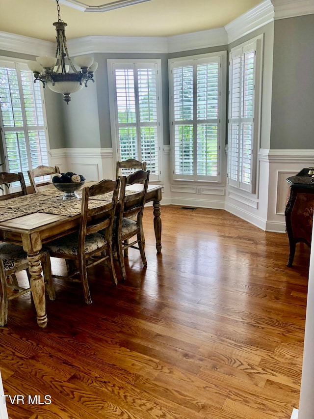 dining space featuring ornamental molding, hardwood / wood-style floors, a notable chandelier, and plenty of natural light