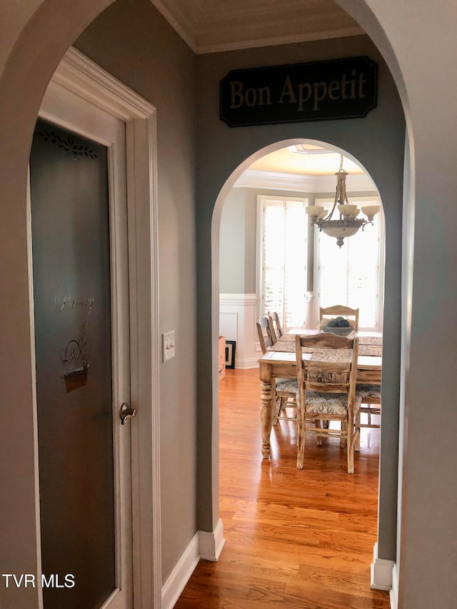 hallway featuring a notable chandelier, ornamental molding, and hardwood / wood-style floors