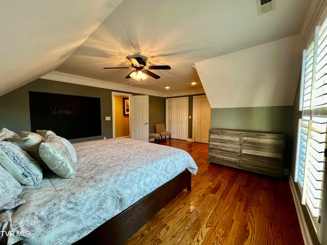 bedroom with dark hardwood / wood-style flooring, ceiling fan, multiple closets, vaulted ceiling, and ornamental molding