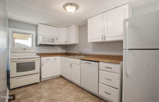 kitchen featuring white appliances, white cabinets, sink, and a textured ceiling