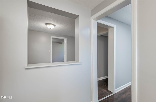 hallway with dark wood-type flooring and a textured ceiling