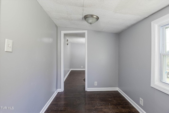 corridor with a textured ceiling, plenty of natural light, and dark hardwood / wood-style floors