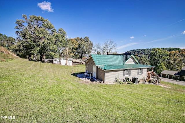 view of property exterior with a lawn and central AC