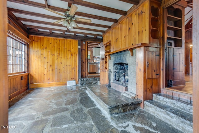120 Rock Rd, Bristol, TN 37620 - unfurnished living room featuring ceiling fan, a fireplace with raised hearth, wooden walls, stone floors, and beamed ceiling