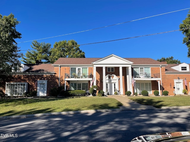 view of front of house featuring a balcony and a front lawn