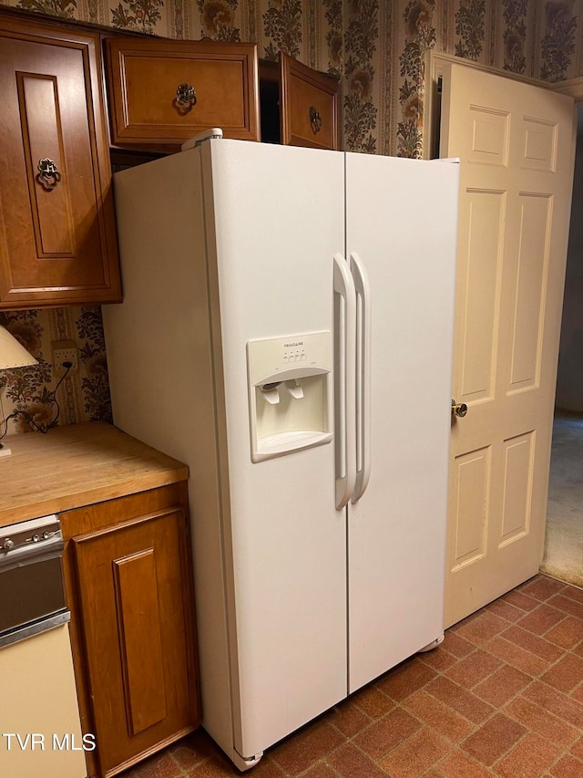 kitchen with white fridge with ice dispenser and carpet floors