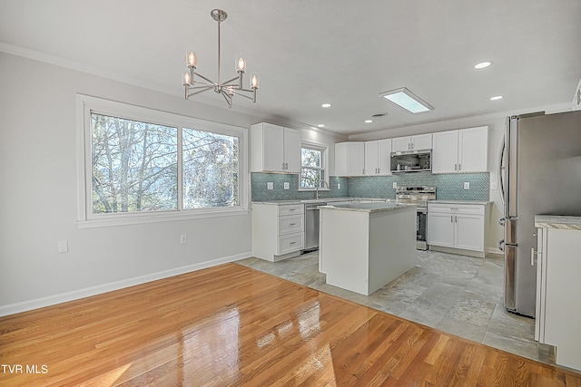 kitchen featuring light hardwood / wood-style flooring, appliances with stainless steel finishes, a kitchen island, and white cabinetry