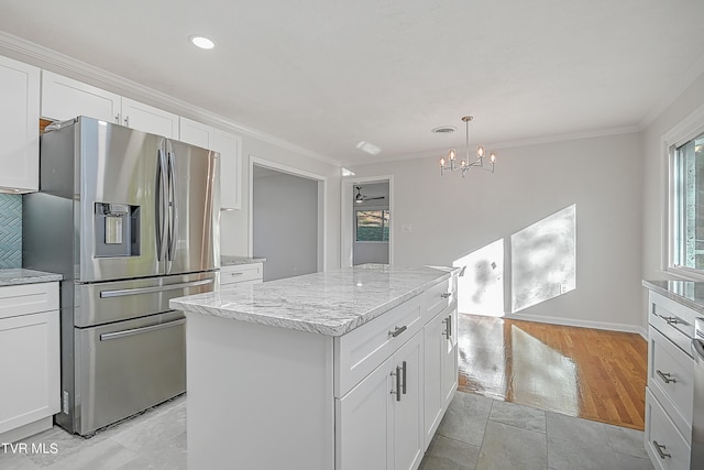 kitchen with stainless steel fridge, a kitchen island, and white cabinetry