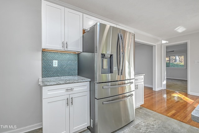 kitchen with light stone counters, white cabinets, stainless steel refrigerator with ice dispenser, and light hardwood / wood-style flooring