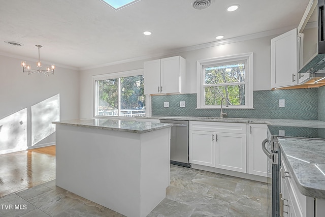 kitchen with plenty of natural light, white cabinets, appliances with stainless steel finishes, and a kitchen island