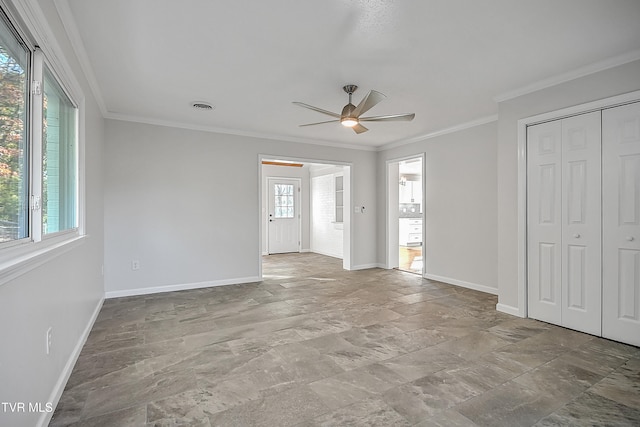 empty room featuring ceiling fan, ornamental molding, and a healthy amount of sunlight