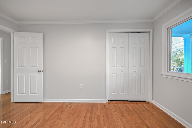 unfurnished bedroom featuring light wood-type flooring, crown molding, and a closet